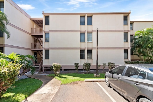 view of property featuring uncovered parking and stairway