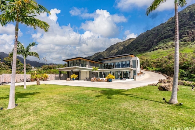 rear view of house with a mountain view, a lawn, a patio, and a balcony