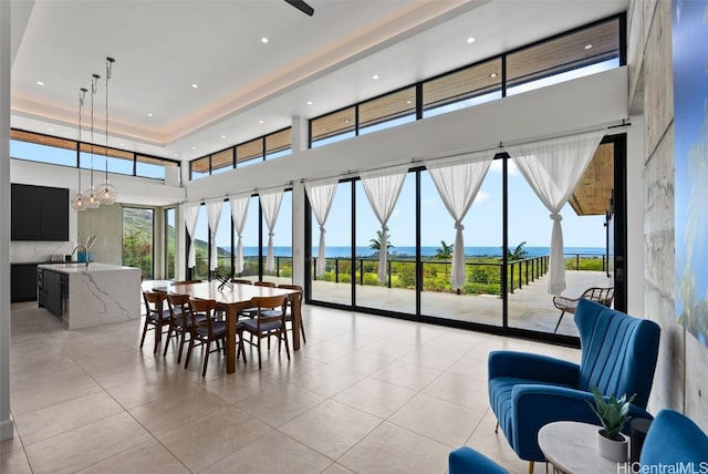 dining space with light tile patterned flooring, a water view, a healthy amount of sunlight, and a chandelier