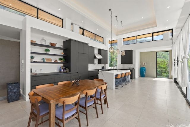 dining area with a raised ceiling, a high ceiling, light tile patterned flooring, and recessed lighting