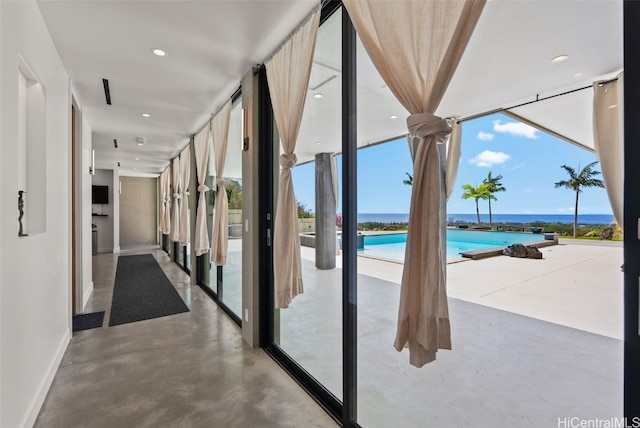 interior space with a water view, finished concrete floors, recessed lighting, a wall of windows, and baseboards