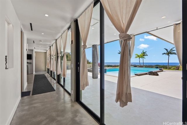 interior space featuring floor to ceiling windows, finished concrete floors, baseboards, a water view, and recessed lighting