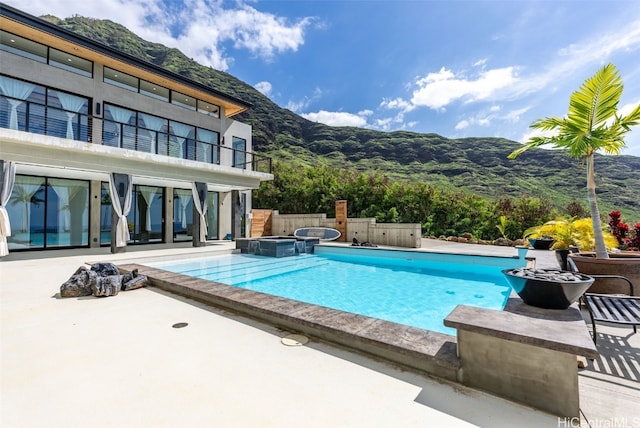 outdoor pool with an in ground hot tub, a patio area, and a mountain view