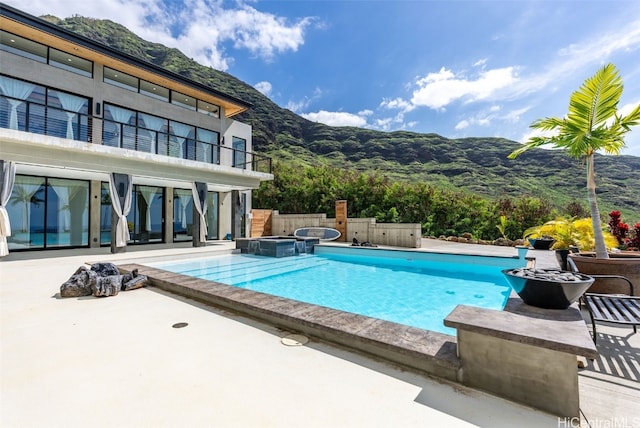pool featuring an in ground hot tub, a patio, and a mountain view