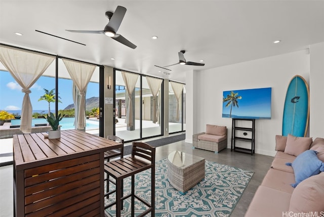 living room featuring a wall of windows, baseboards, concrete flooring, and recessed lighting