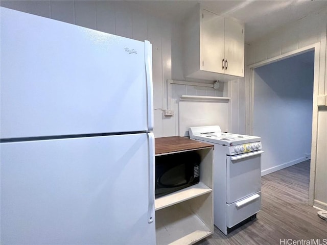 kitchen featuring white appliances, wood-type flooring, and white cabinets