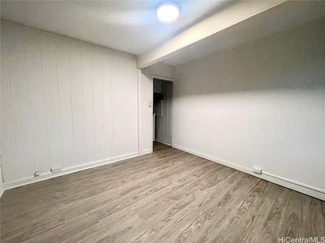 unfurnished room with light hardwood / wood-style flooring, a baseboard radiator, and beam ceiling