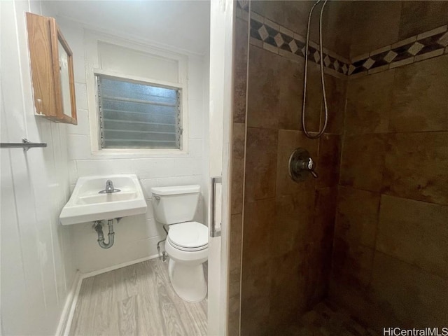 bathroom featuring sink, toilet, hardwood / wood-style floors, and tiled shower