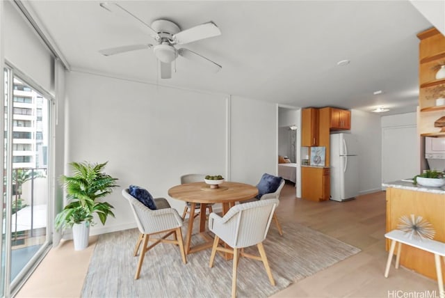 dining space with ceiling fan and light wood-type flooring