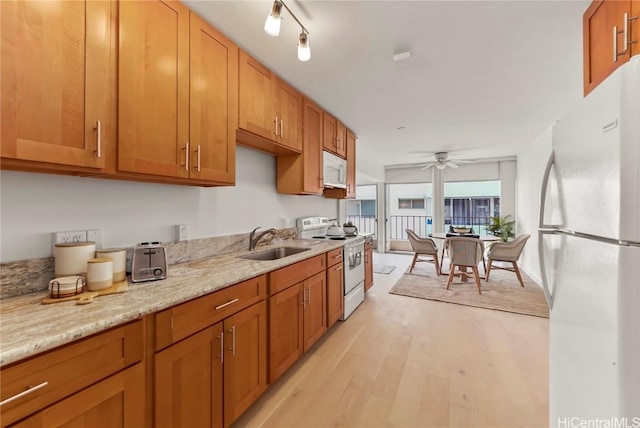 kitchen with sink, ceiling fan, light stone counters, white appliances, and light hardwood / wood-style flooring