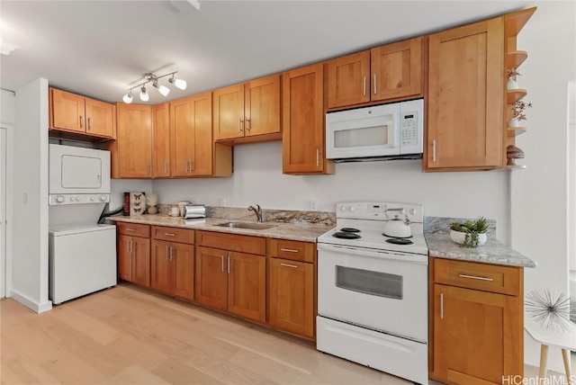 kitchen with sink, white appliances, stacked washer / dryer, light stone countertops, and light hardwood / wood-style floors