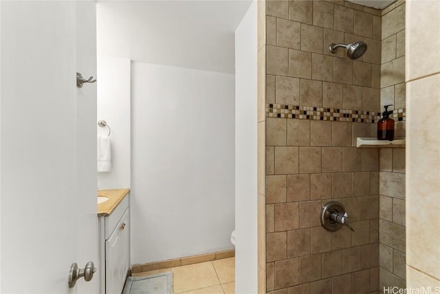 bathroom featuring tile patterned floors, toilet, vanity, and a tile shower