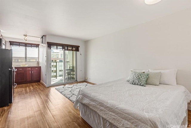 bedroom featuring hardwood / wood-style flooring, black refrigerator, and access to exterior