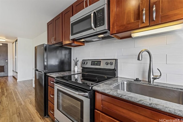 kitchen with sink, decorative backsplash, light hardwood / wood-style floors, stainless steel appliances, and light stone countertops