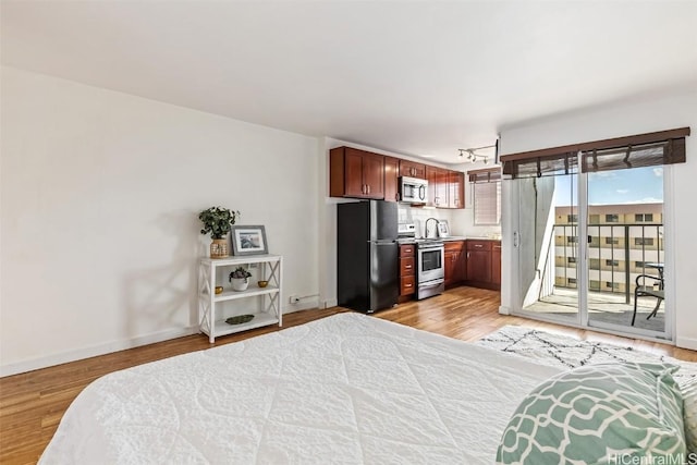 bedroom featuring stainless steel refrigerator, access to exterior, and light hardwood / wood-style floors