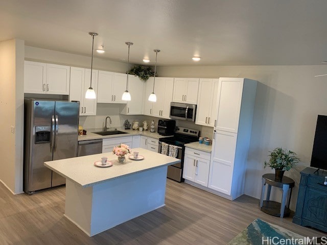 kitchen featuring white cabinetry, hanging light fixtures, and appliances with stainless steel finishes