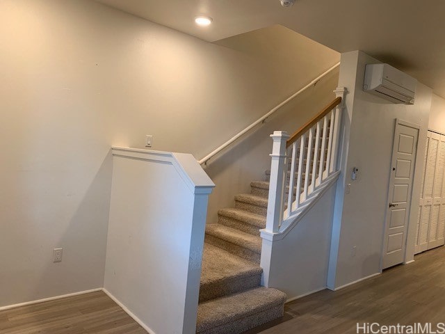 staircase with a wall mounted air conditioner and hardwood / wood-style floors