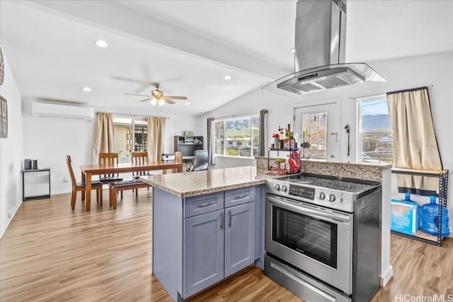 kitchen with electric stove, a wall mounted air conditioner, island exhaust hood, gray cabinets, and light wood-type flooring