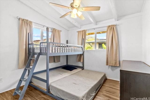 bedroom with lofted ceiling with beams and wood finished floors