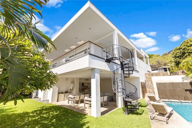 back of property with a balcony, a yard, and a patio area