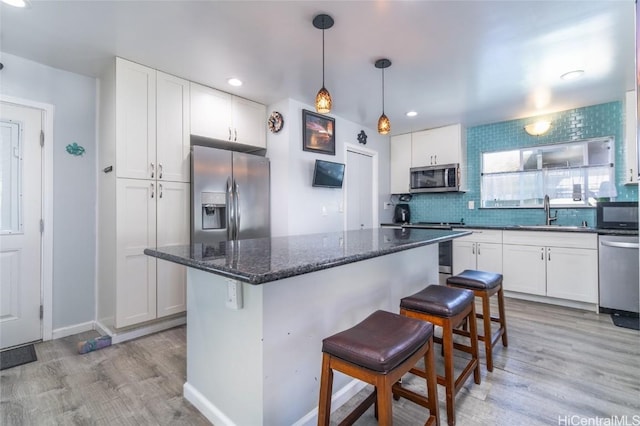 kitchen with a kitchen bar, sink, a center island, stainless steel appliances, and white cabinets