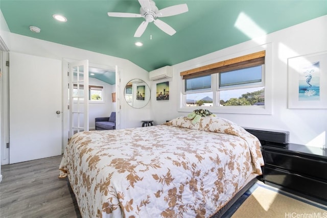 bedroom featuring hardwood / wood-style flooring, vaulted ceiling, a wall unit AC, and ceiling fan