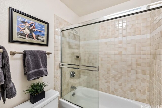 bathroom with combined bath / shower with glass door and toilet