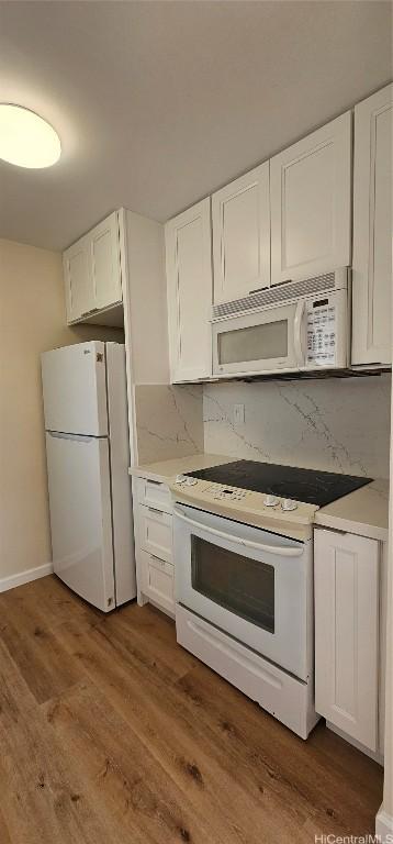 kitchen with white cabinetry, hardwood / wood-style floors, white appliances, and decorative backsplash