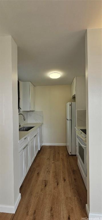 kitchen featuring white cabinetry, sink, white appliances, and dark wood-type flooring