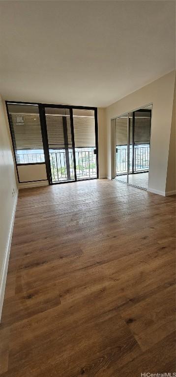 unfurnished room featuring floor to ceiling windows and dark hardwood / wood-style flooring