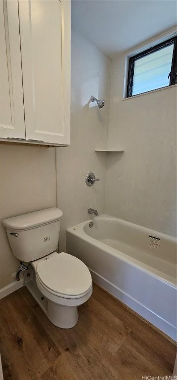 bathroom featuring wood-type flooring, tub / shower combination, and toilet