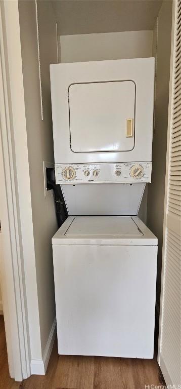 laundry room with stacked washer / drying machine and dark hardwood / wood-style flooring