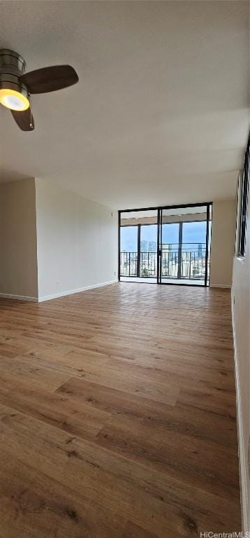 spare room featuring hardwood / wood-style floors, a wall of windows, and ceiling fan