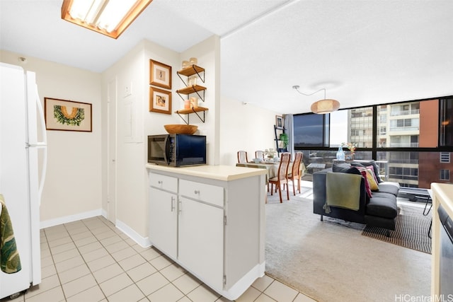 kitchen featuring light colored carpet, white fridge, and white cabinets