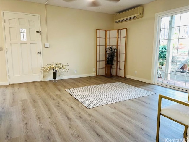 entrance foyer featuring a wall mounted air conditioner, light hardwood / wood-style floors, and ceiling fan