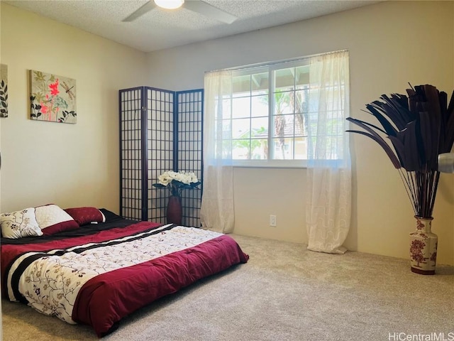 carpeted bedroom featuring ceiling fan and a textured ceiling