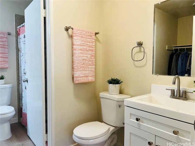 bathroom with hardwood / wood-style flooring, vanity, and toilet