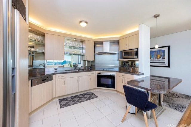 kitchen with wall chimney exhaust hood, sink, hanging light fixtures, dark stone countertops, and stainless steel appliances