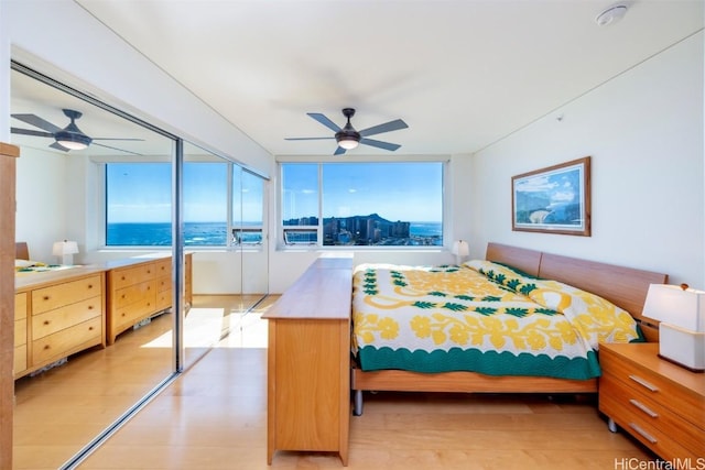 bedroom featuring ceiling fan, light hardwood / wood-style floors, and multiple windows