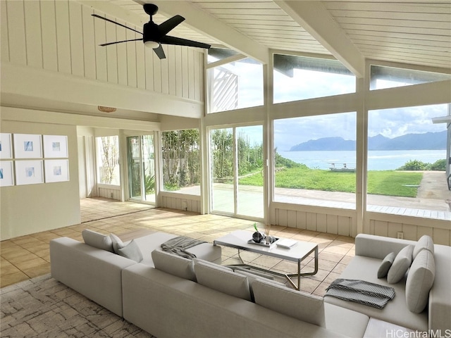 sunroom / solarium with a water and mountain view, lofted ceiling with beams, and ceiling fan