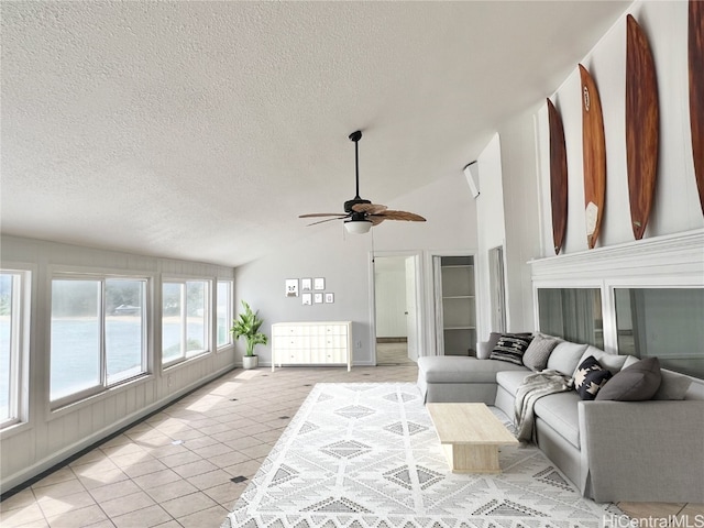 living room with ceiling fan, vaulted ceiling, a textured ceiling, and light tile patterned floors