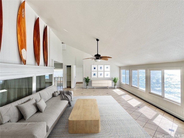 living room featuring ceiling fan, lofted ceiling, a textured ceiling, and light tile patterned floors