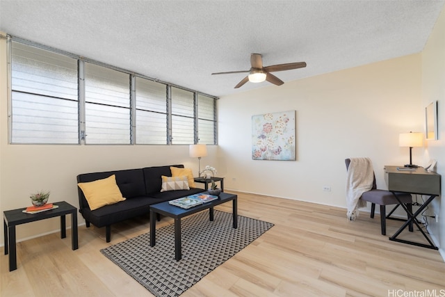 living room with ceiling fan, a textured ceiling, and light hardwood / wood-style flooring