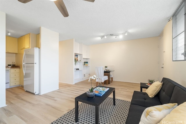 living room featuring ceiling fan, light hardwood / wood-style floors, and a textured ceiling