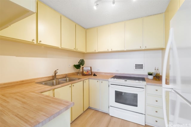 kitchen with white appliances, cream cabinets, and sink