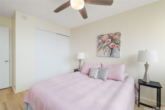 bedroom featuring ceiling fan, light hardwood / wood-style floors, a closet, and a textured ceiling