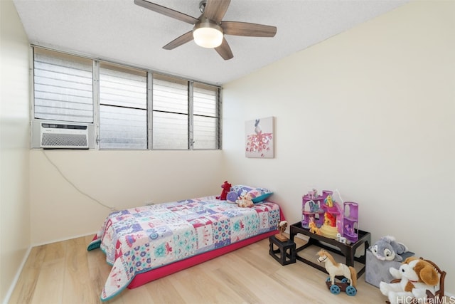 bedroom with ceiling fan, hardwood / wood-style floors, a textured ceiling, and cooling unit