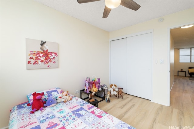 bedroom featuring hardwood / wood-style flooring, ceiling fan, a closet, and a textured ceiling