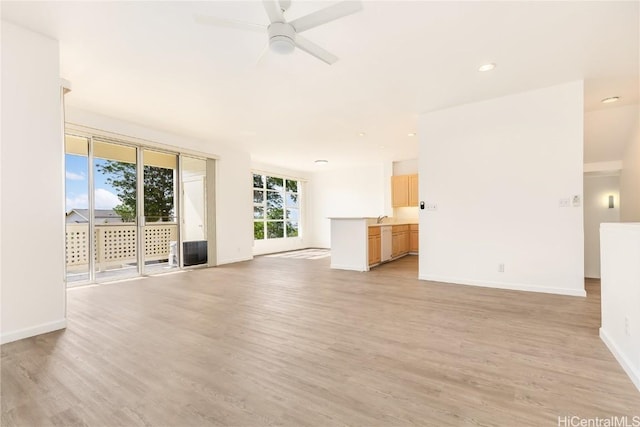 unfurnished living room with sink, light hardwood / wood-style flooring, and ceiling fan