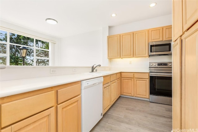 kitchen with sink, light brown cabinets, light hardwood / wood-style floors, and appliances with stainless steel finishes